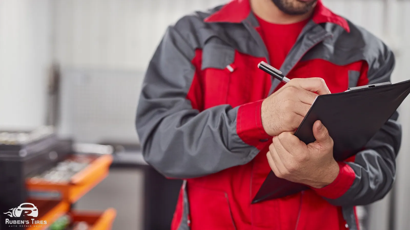 Mechanic in red uniform documenting vehicle inspection details at Ruben's Tires in Apopka.