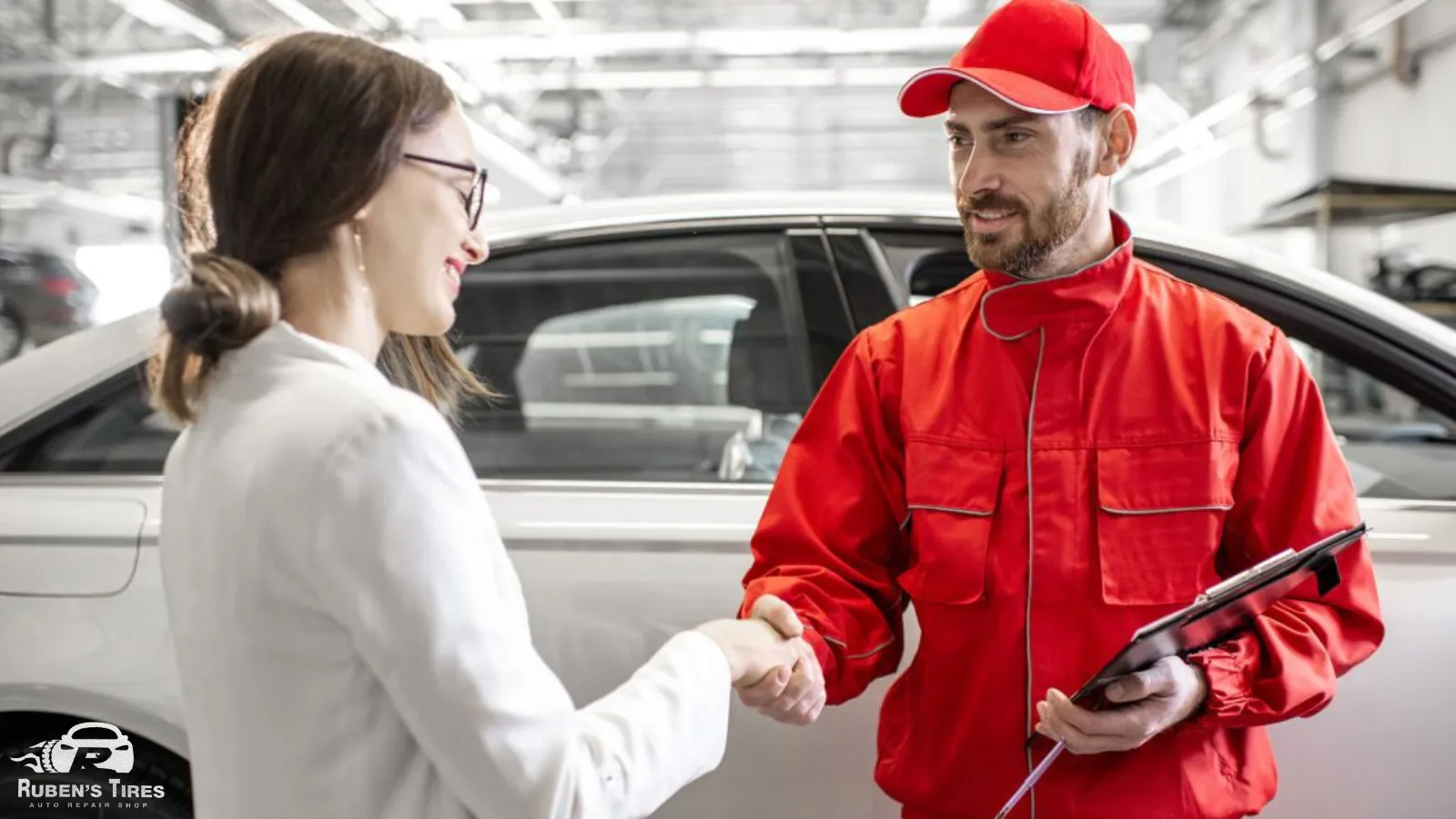 Mechanic in red uniform shaking hands with a satisfied customer at Ruben's Tires in Apopka.