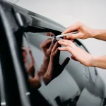 Technician carefully applying film to a car window, showcasing expert precision and quality service for Window Tinting Apopka at Ruben’s Tires.
