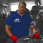 Ruben’s Tires technician smiling while handling a tire in the shop, representing reliable and professional Auto Repair Apopka services with a customer-first approach.