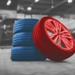 Stack of blue tires and a red custom wheel displayed in a service bay, representing quality products and expert service at a trusted Tire Shop Apopka.